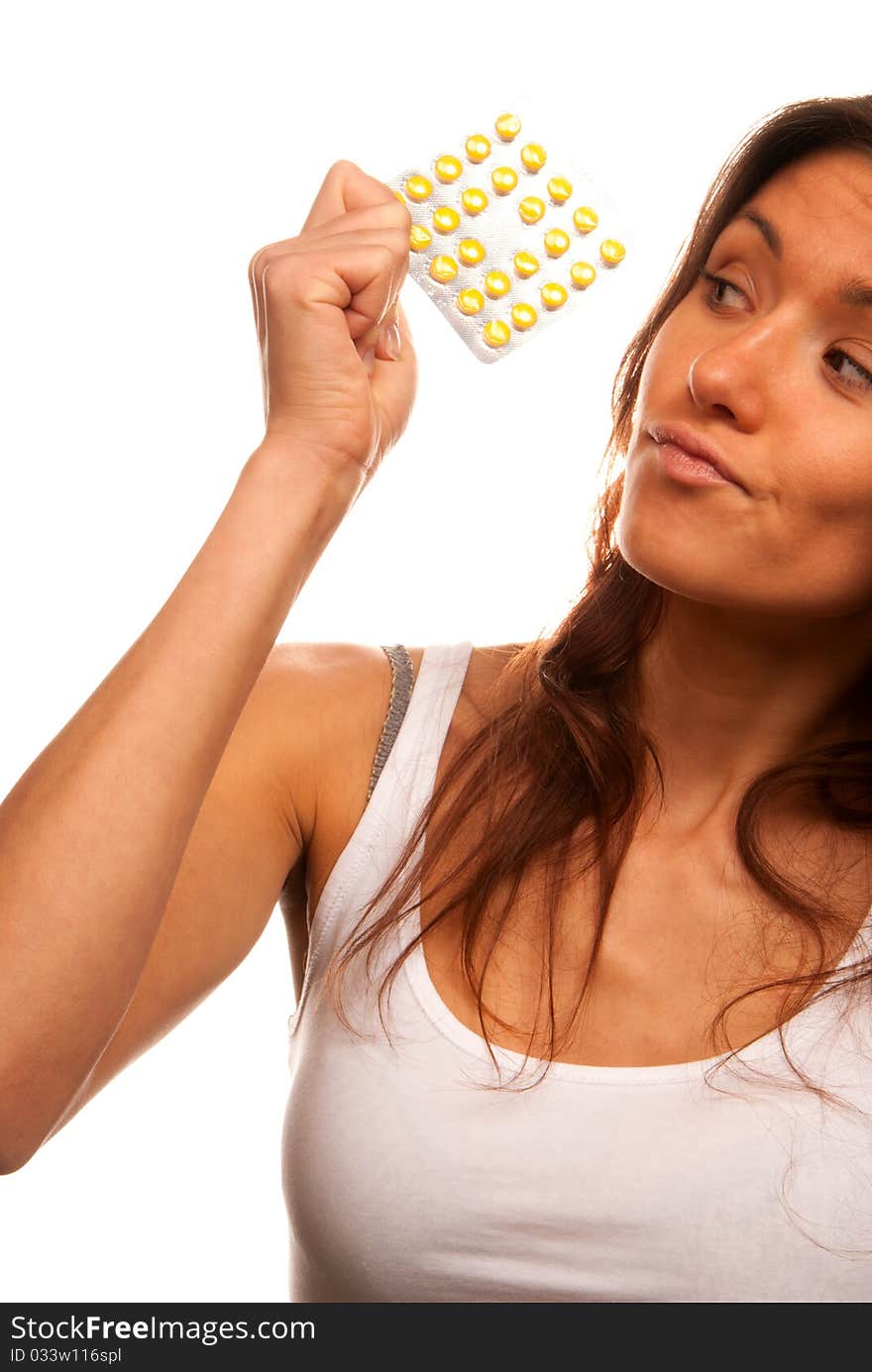 Pretty young woman looking at full medicine pack of yellow tablet pills thinking about doctor's prescription to take one or not isolated on a white background. Pretty young woman looking at full medicine pack of yellow tablet pills thinking about doctor's prescription to take one or not isolated on a white background