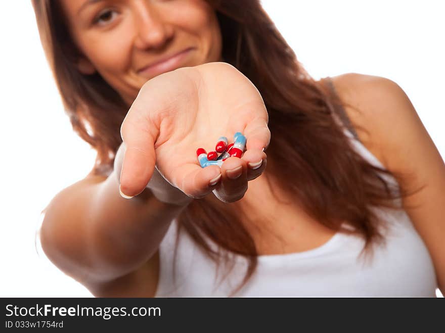 Young woman doctor offering pill capsules red and blue to the patient in hand isolated on a white background