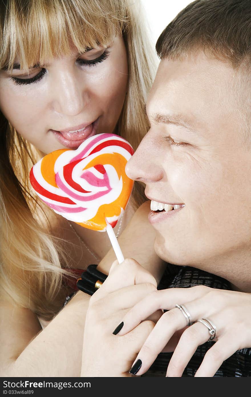 The young couple licking lollypop shape of heart. The young couple licking lollypop shape of heart