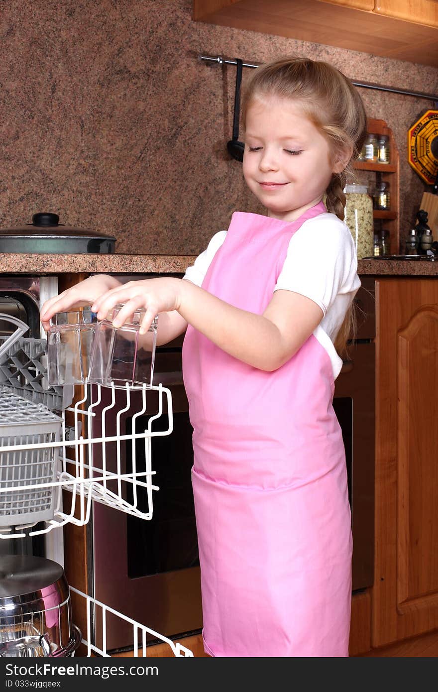 Little girl taken clear glass from dishwasher in the kitchen