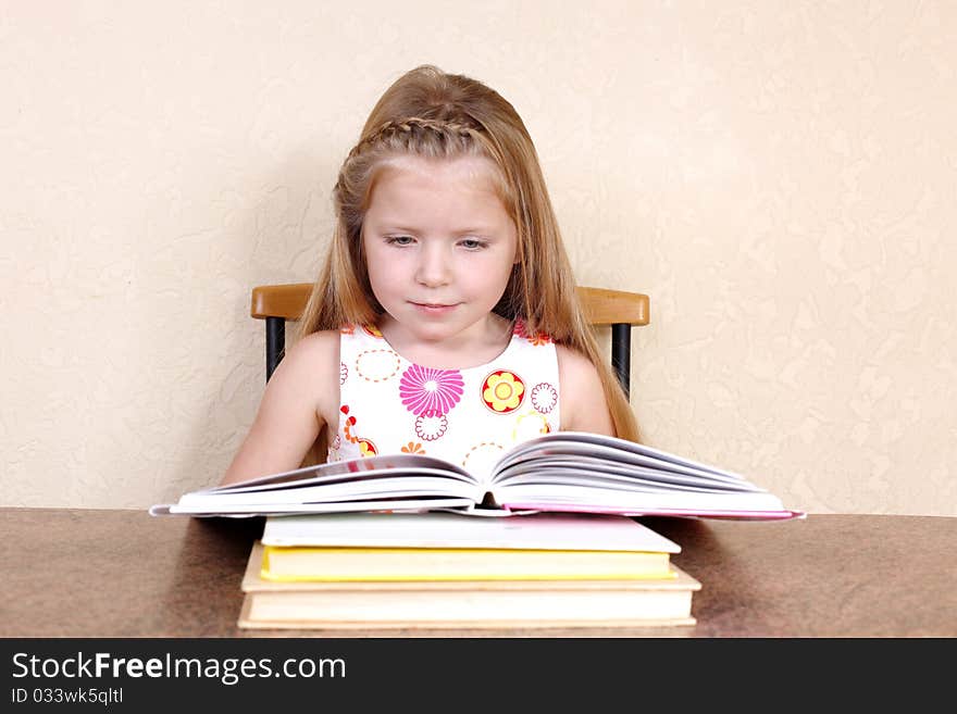 Little girl reading book against yellow wall at home