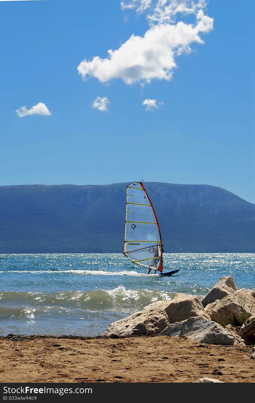 Surfer on the blue sea with island and blue sky in background