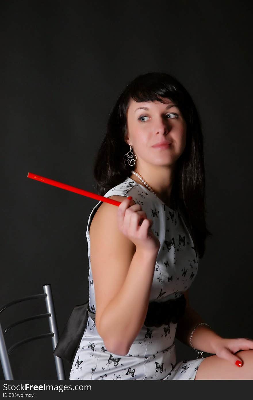 Brunette on a dark background with a red pencil. Brunette on a dark background with a red pencil