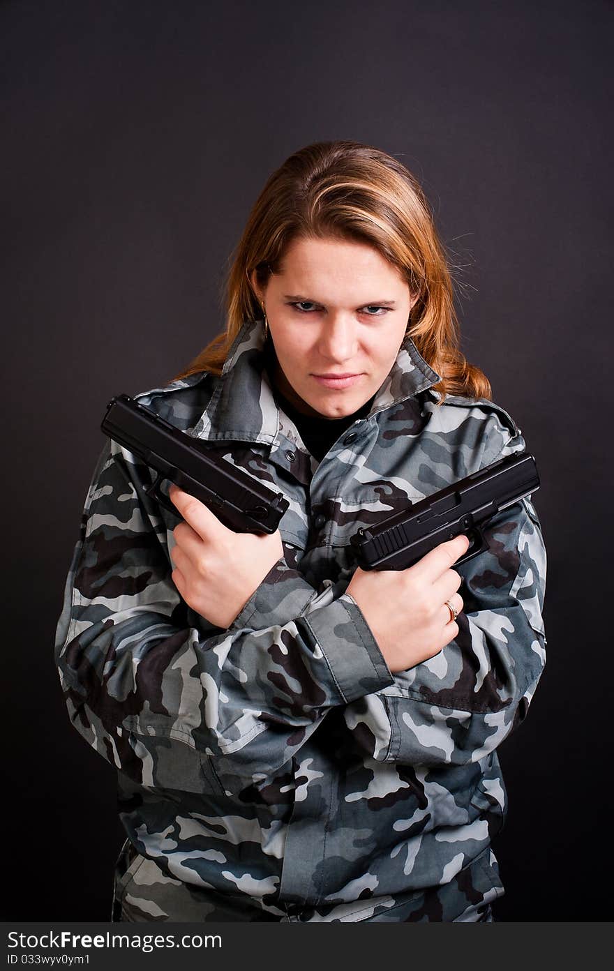 Girl in a camouflage clothing holding guns. Girl in a camouflage clothing holding guns