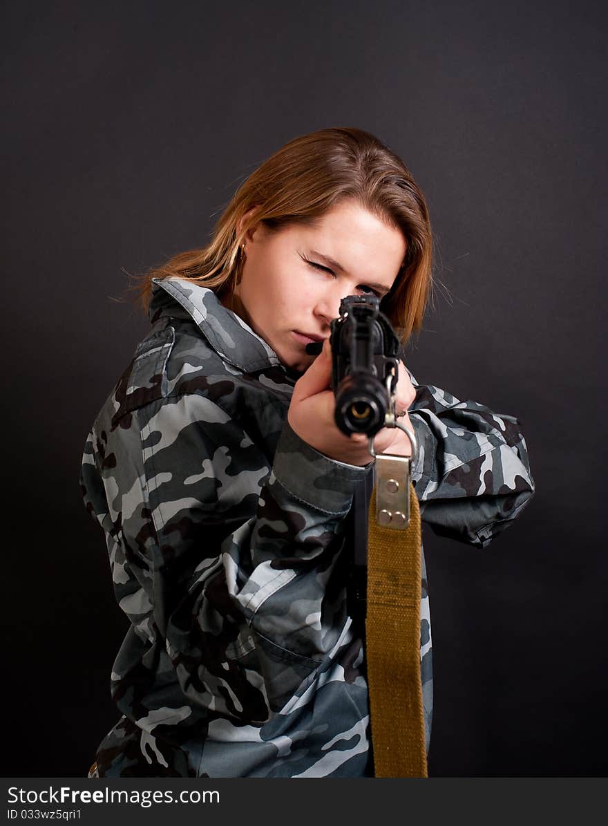 Girl in a camouflage clothing holding gun. Girl in a camouflage clothing holding gun