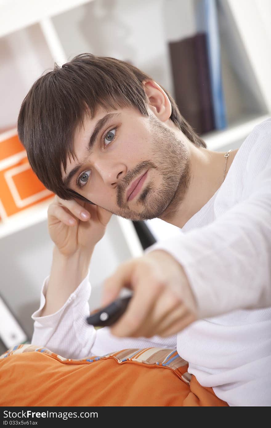 Young man with remote control watching television