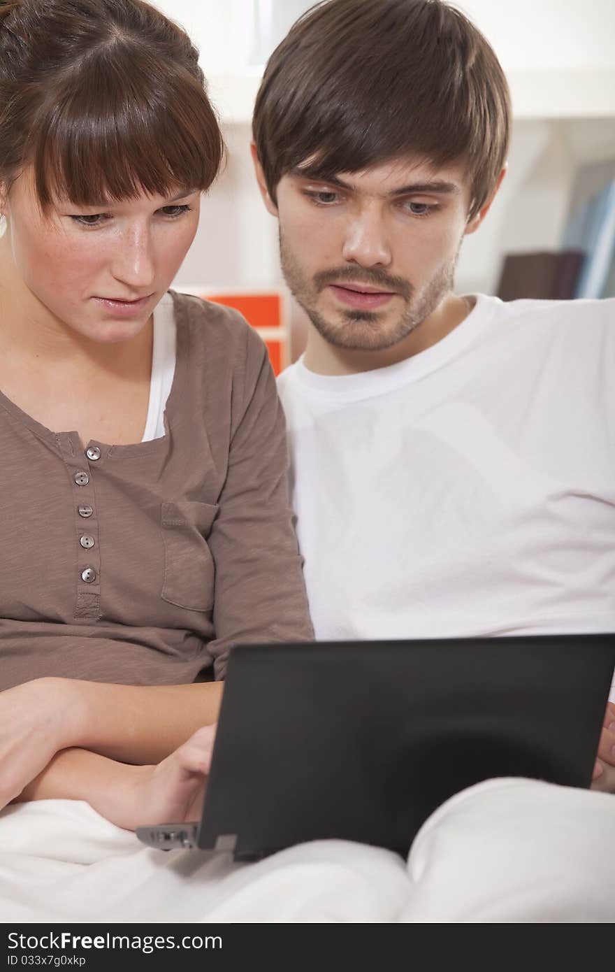 Young couple with laptop computer sitting on sofa. Young couple with laptop computer sitting on sofa