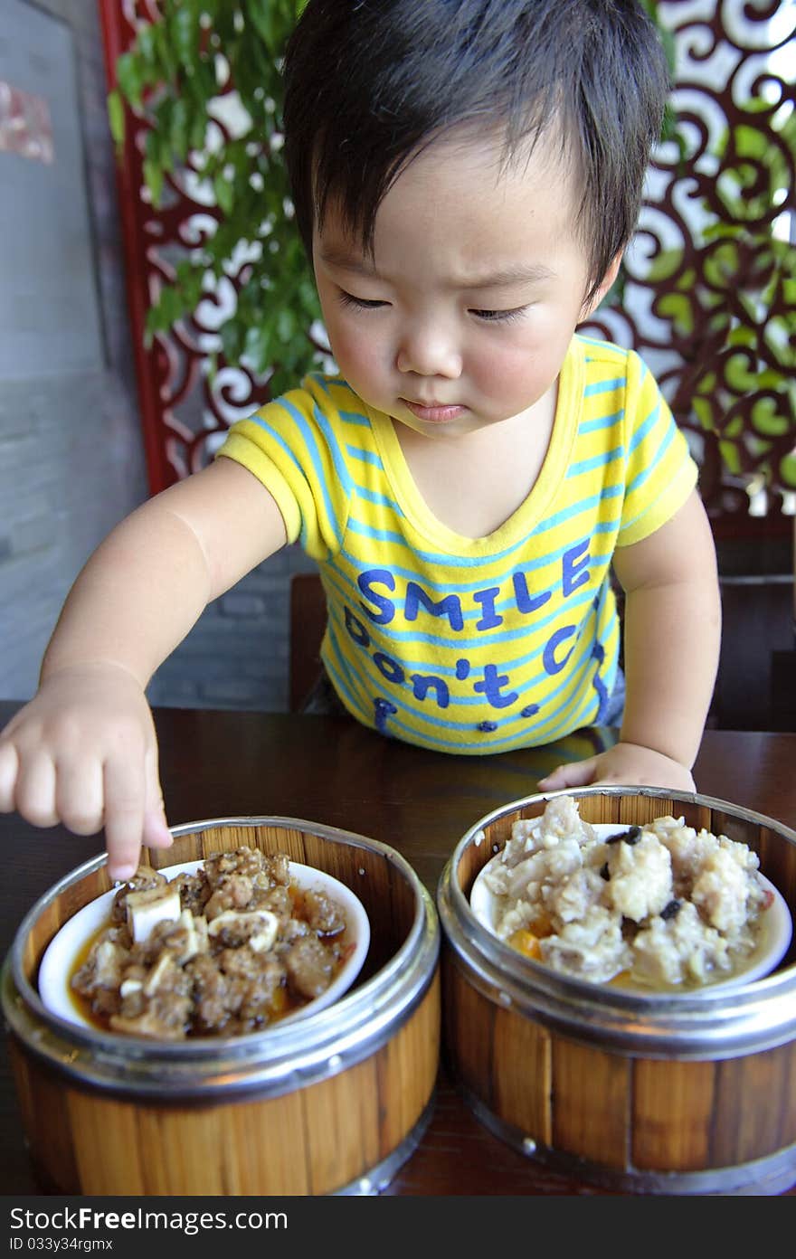 A cute baby is eating in a restaurant. A cute baby is eating in a restaurant