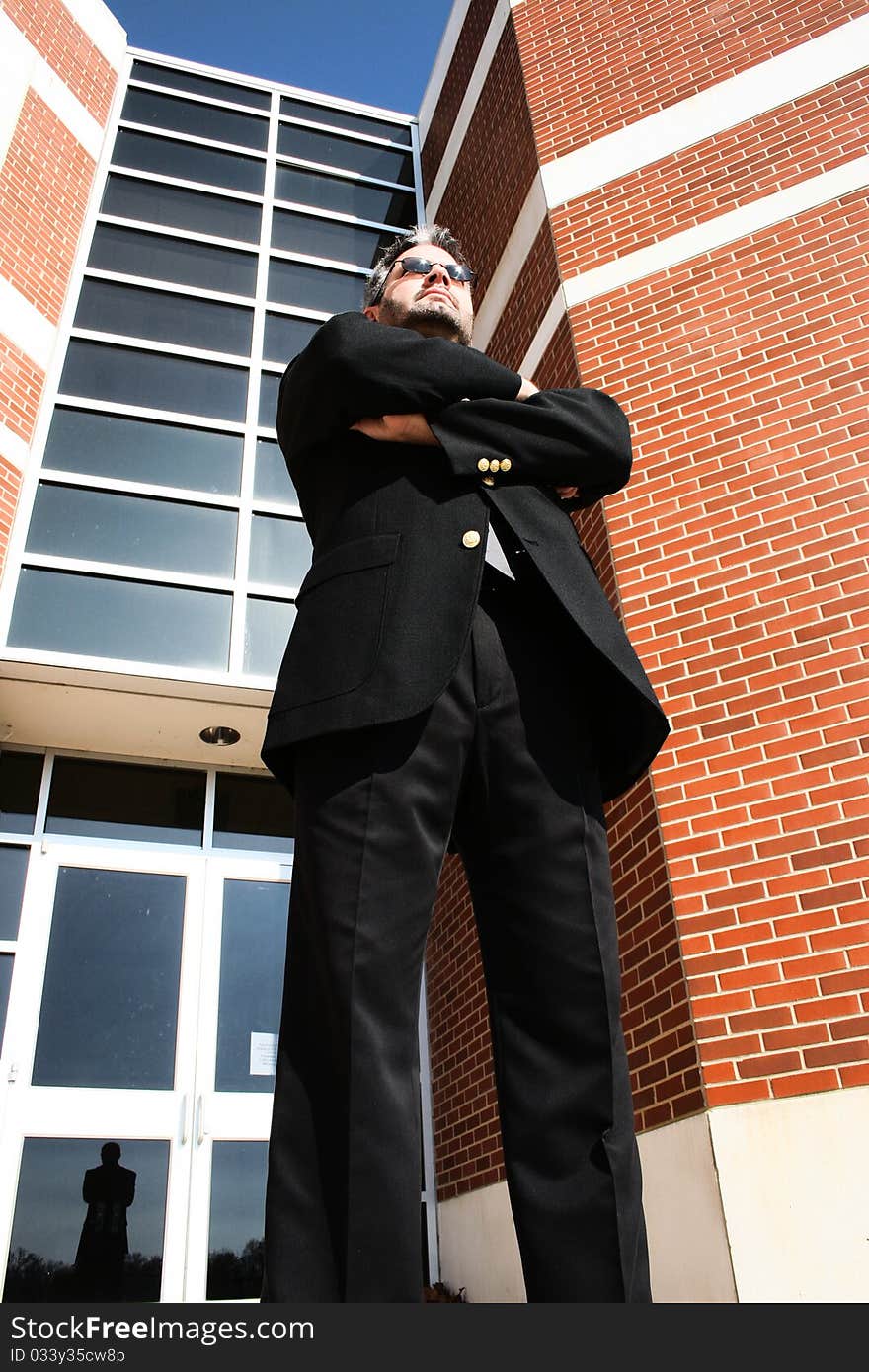 Attractive 40 year old business man in suit and sunglasses walking standing arms crossed serious office building. Attractive 40 year old business man in suit and sunglasses walking standing arms crossed serious office building.