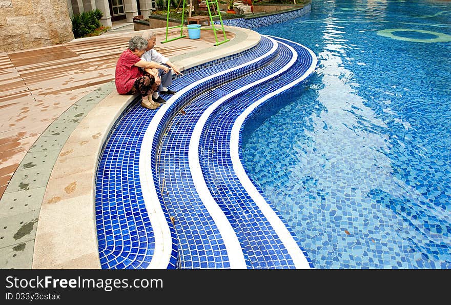 An intimate senior couple sitting beside a pool. An intimate senior couple sitting beside a pool