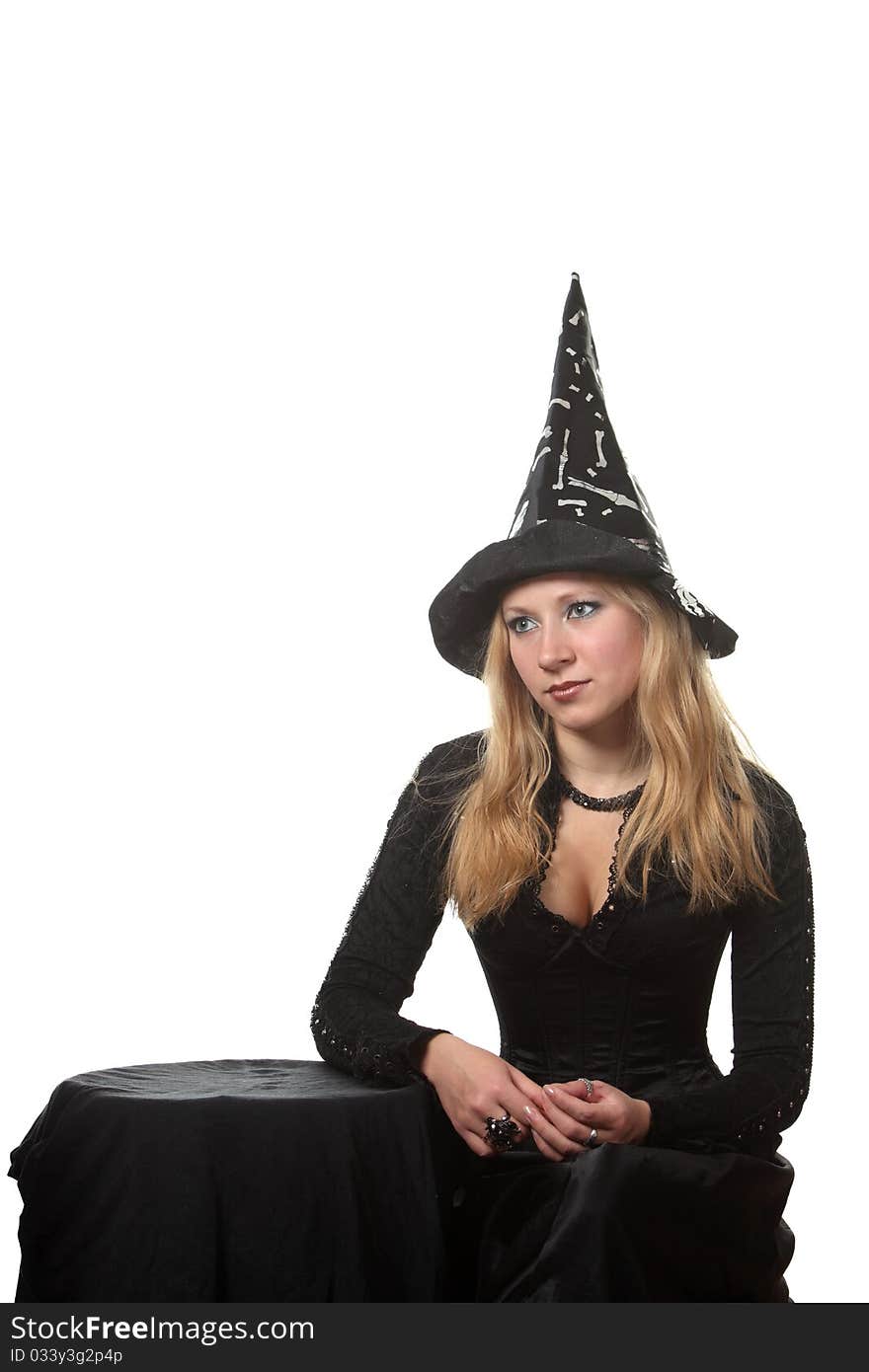 A young woman in a witch costume sit near the table