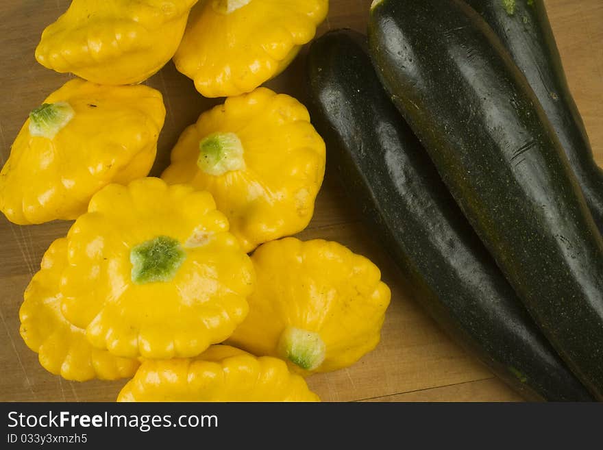 Raw uncooked green and yellow marrow squash pumpkin vegetables on a wooden surface. Raw uncooked green and yellow marrow squash pumpkin vegetables on a wooden surface