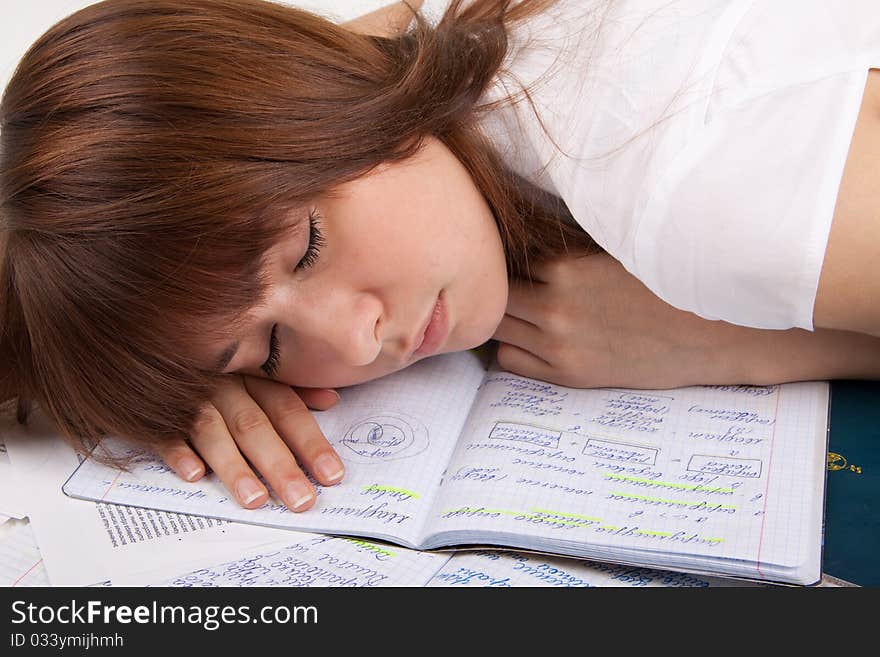 The girl has fallen asleep on writing-books. The girl has fallen asleep on writing-books