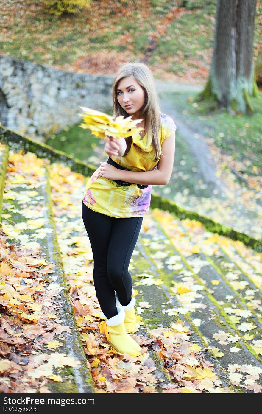 Young beauty with autumn leaves in park