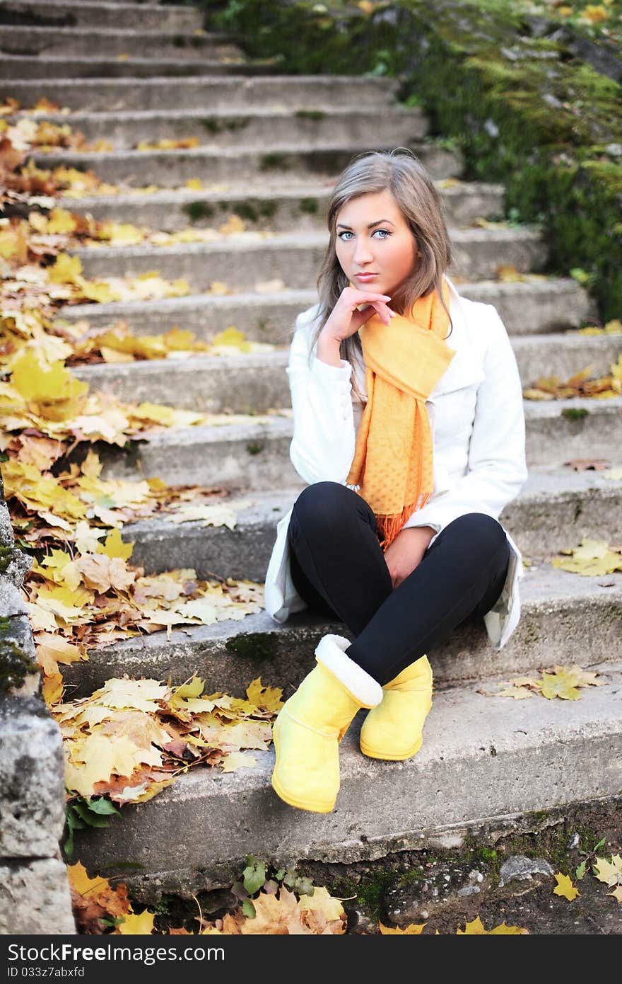 Adorable woman sitting on stairs in autumn park