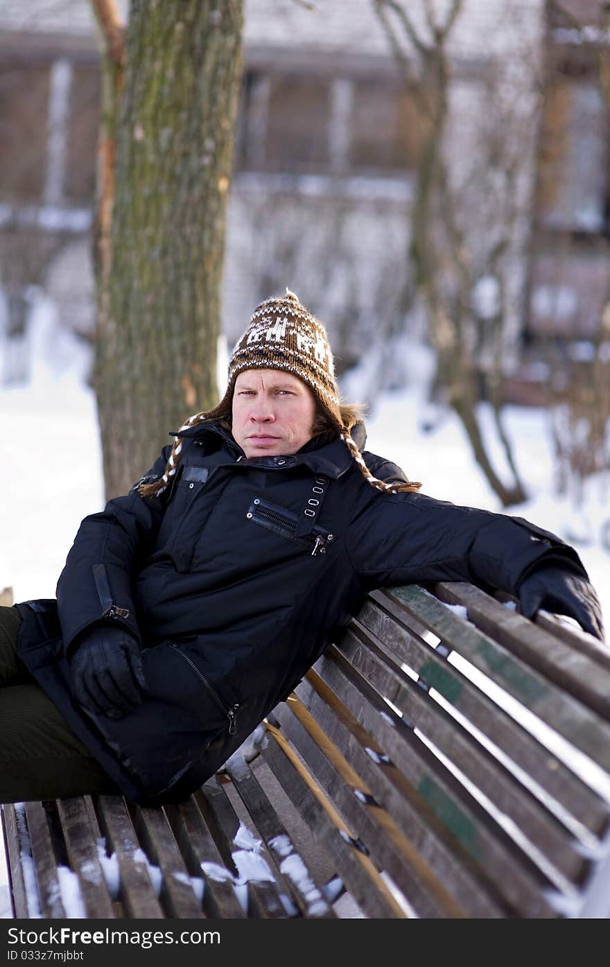 Portrait of adult man on bench in winter time