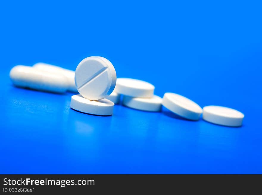 Extreme closeup of few pills on blue background with copy space