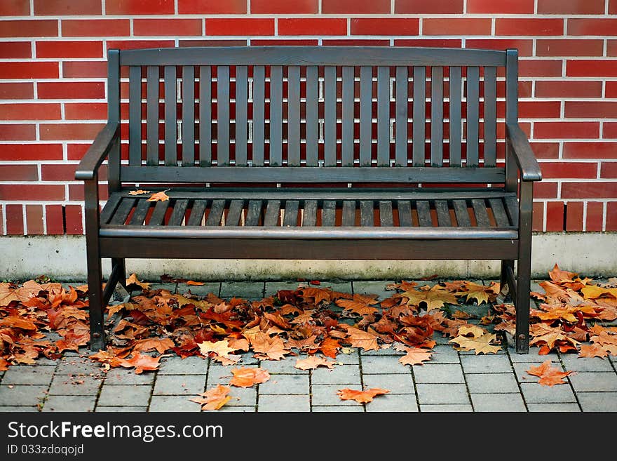 Modern bench in front of red brick wall - autumn urban scene