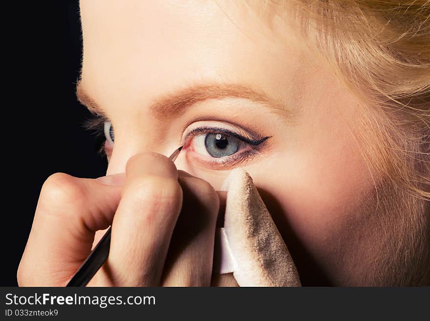 Charming young woman applying blusher eyelid. Close-up view.