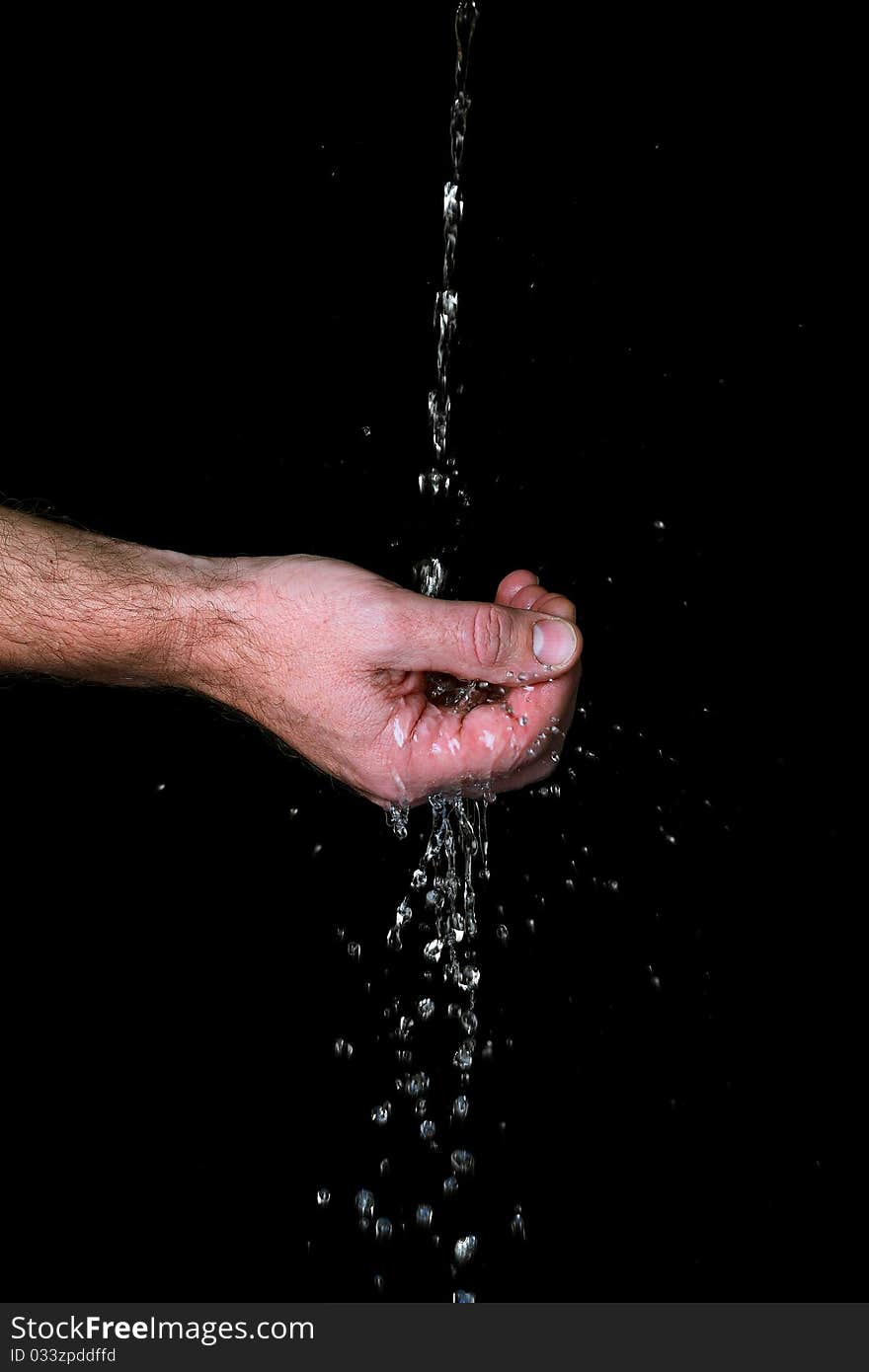 Water runs trough the fingers, against black background