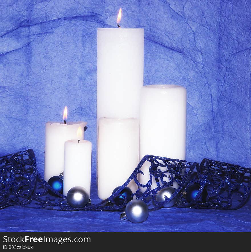 White burning candles with decorations and blue ribbon. White burning candles with decorations and blue ribbon