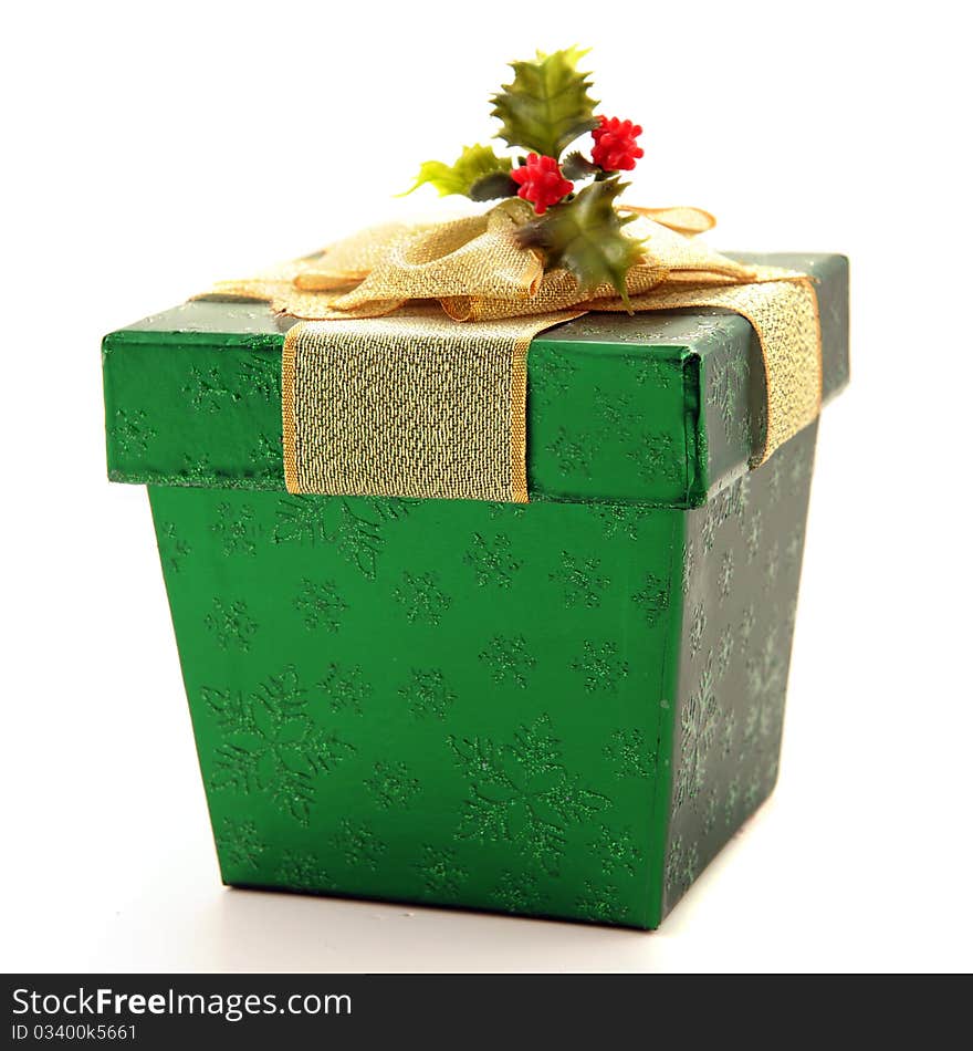 A shiny green gift box with a broad gold ribbon and a sprig of holly. Isolated on white. A shiny green gift box with a broad gold ribbon and a sprig of holly. Isolated on white.