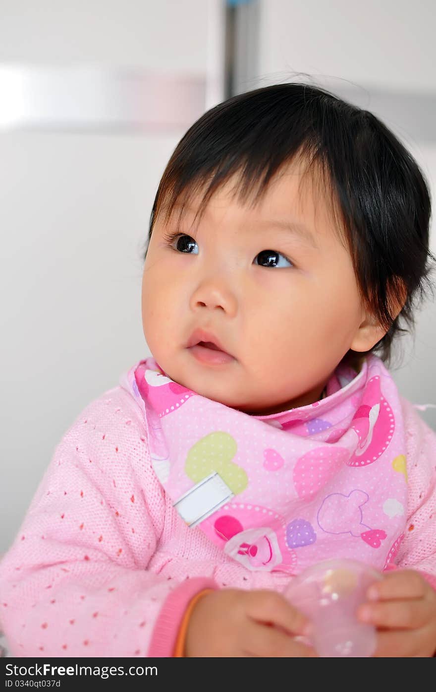 A Asian baby girl sitting on the bed