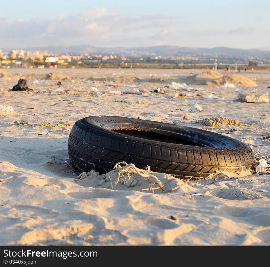 Garbage thrown on the shore by the sea after a storm; in this picture a car wheel appears as the main subject due to its more pronounced detail among other objects. Garbage thrown on the shore by the sea after a storm; in this picture a car wheel appears as the main subject due to its more pronounced detail among other objects