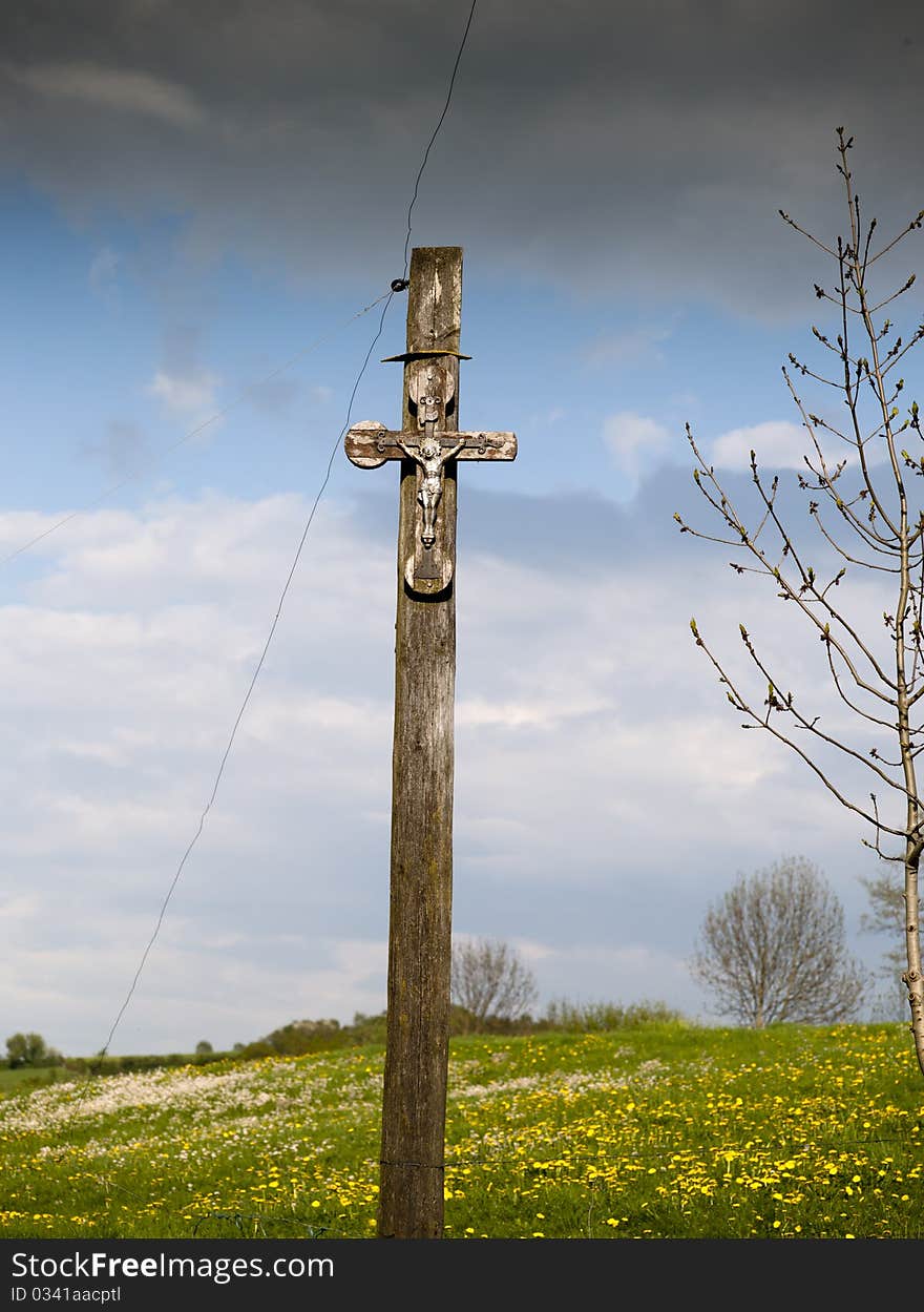 Crucifix in field in the background yellow flowers