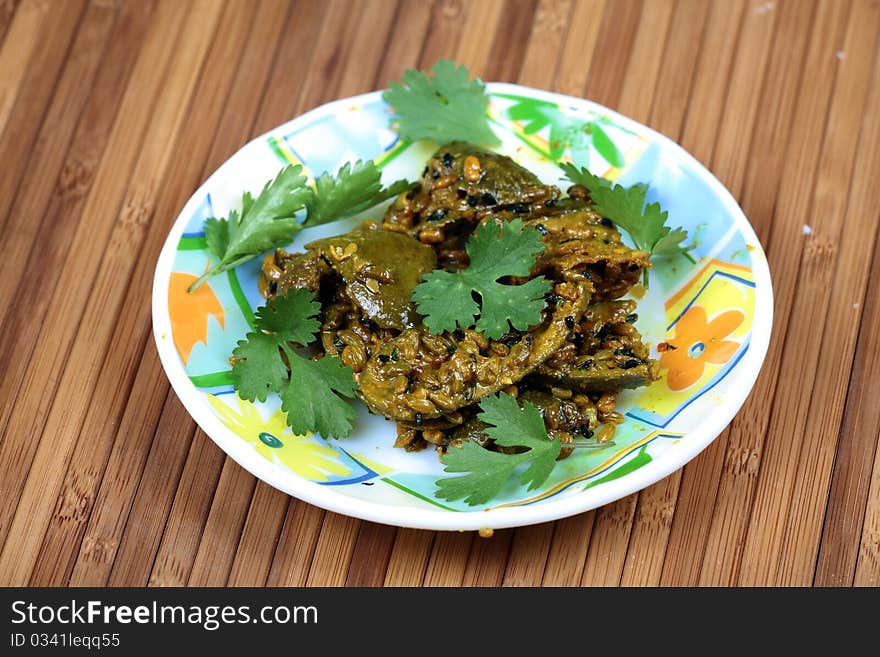 Home-made mango pickle in white plate over wooden background.