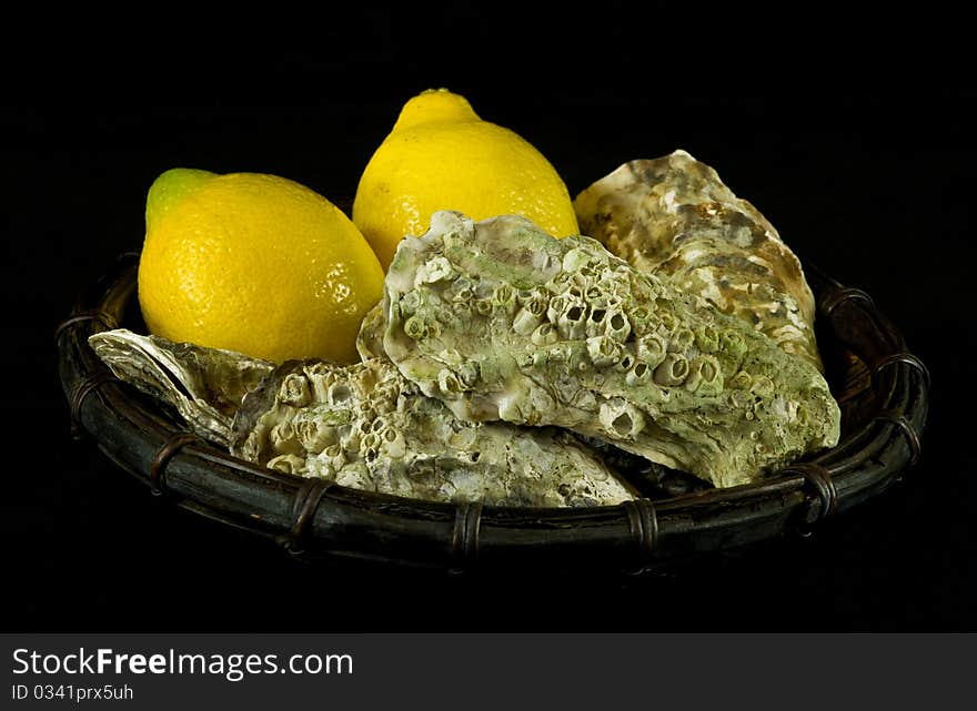 Oysters and lemons in a basket on black background