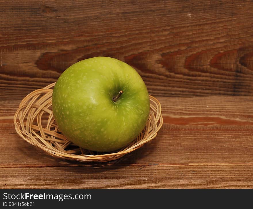 Ripe apple in basket on wood background