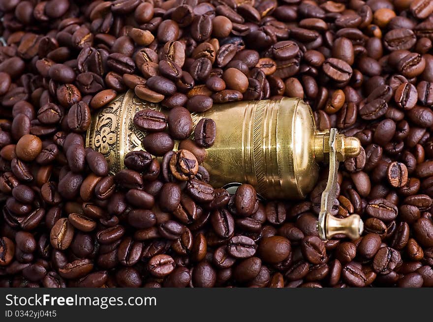 Ancient gold coffee grinder in coffee beans close up.