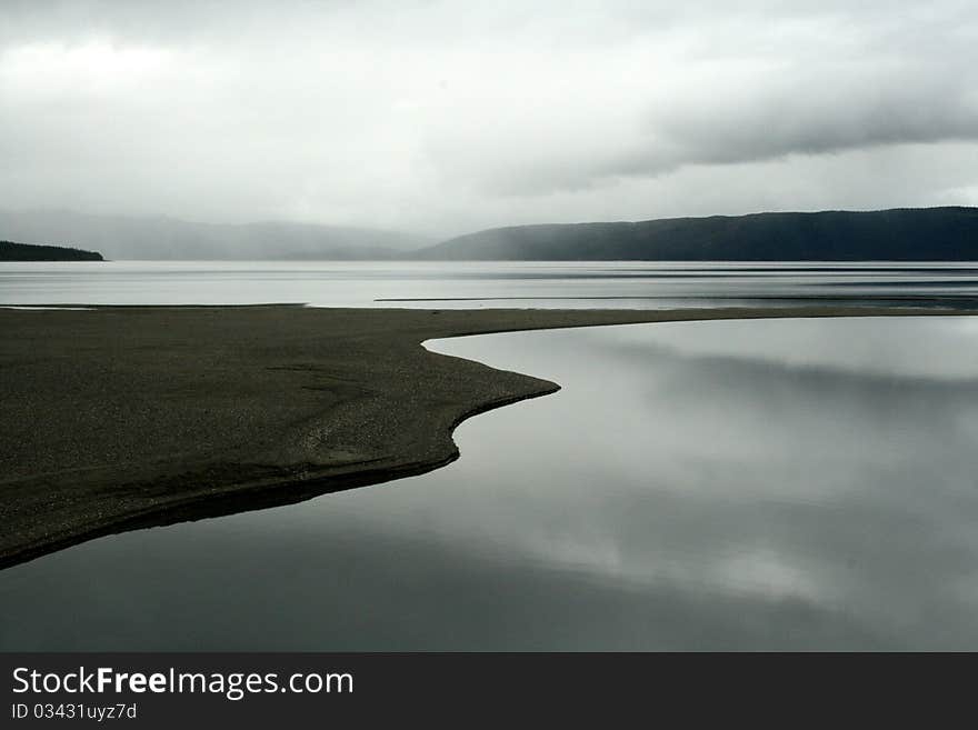 A large lake with a sand bank, high mountains on the horizon. A large lake with a sand bank, high mountains on the horizon.