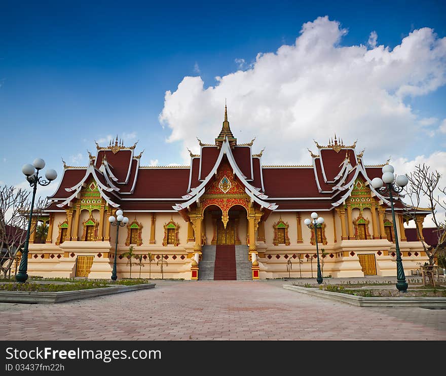 The Buddhist sanctuary in front of blue sky and white cloud with brick pathway foreground.