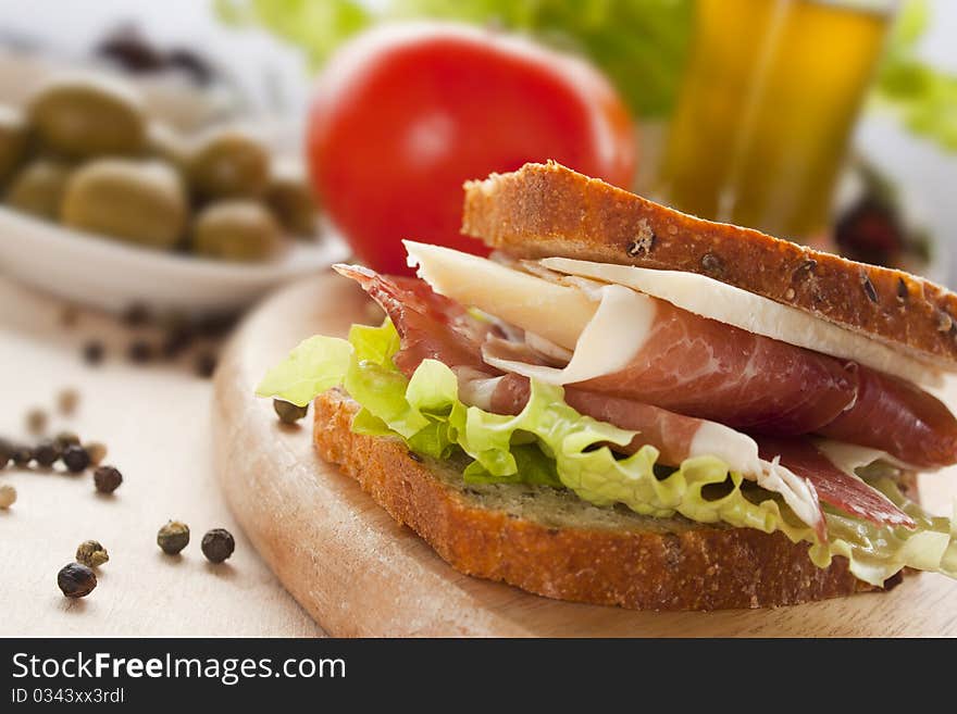 Prosciutto and cheese sandwich with olives and lettuce.