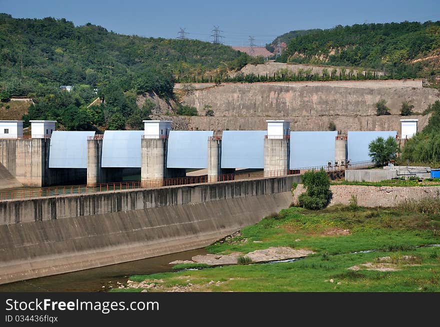 Gate of water electricity plant on yellow river in China, as big construction made by concrete built beside yellow river and hill