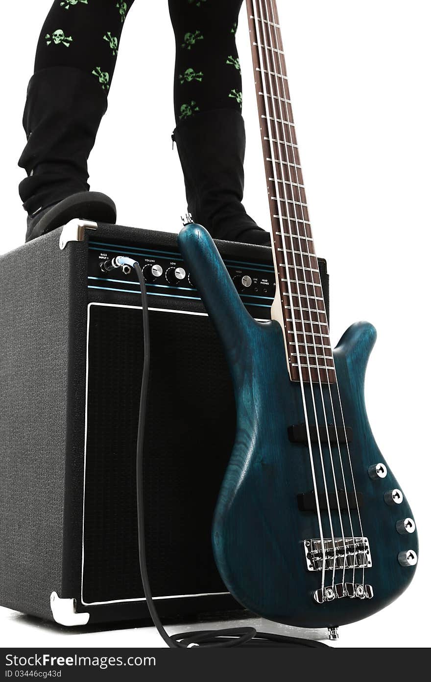 Amp and 5 string bass guitar over white with female boots legs standing on amp.