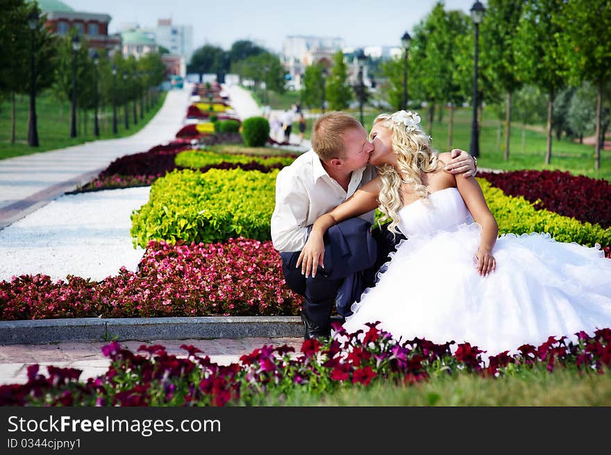 Happy bride and groom at a wedding a walk in the park surrounded by flowers. Happy bride and groom at a wedding a walk in the park surrounded by flowers