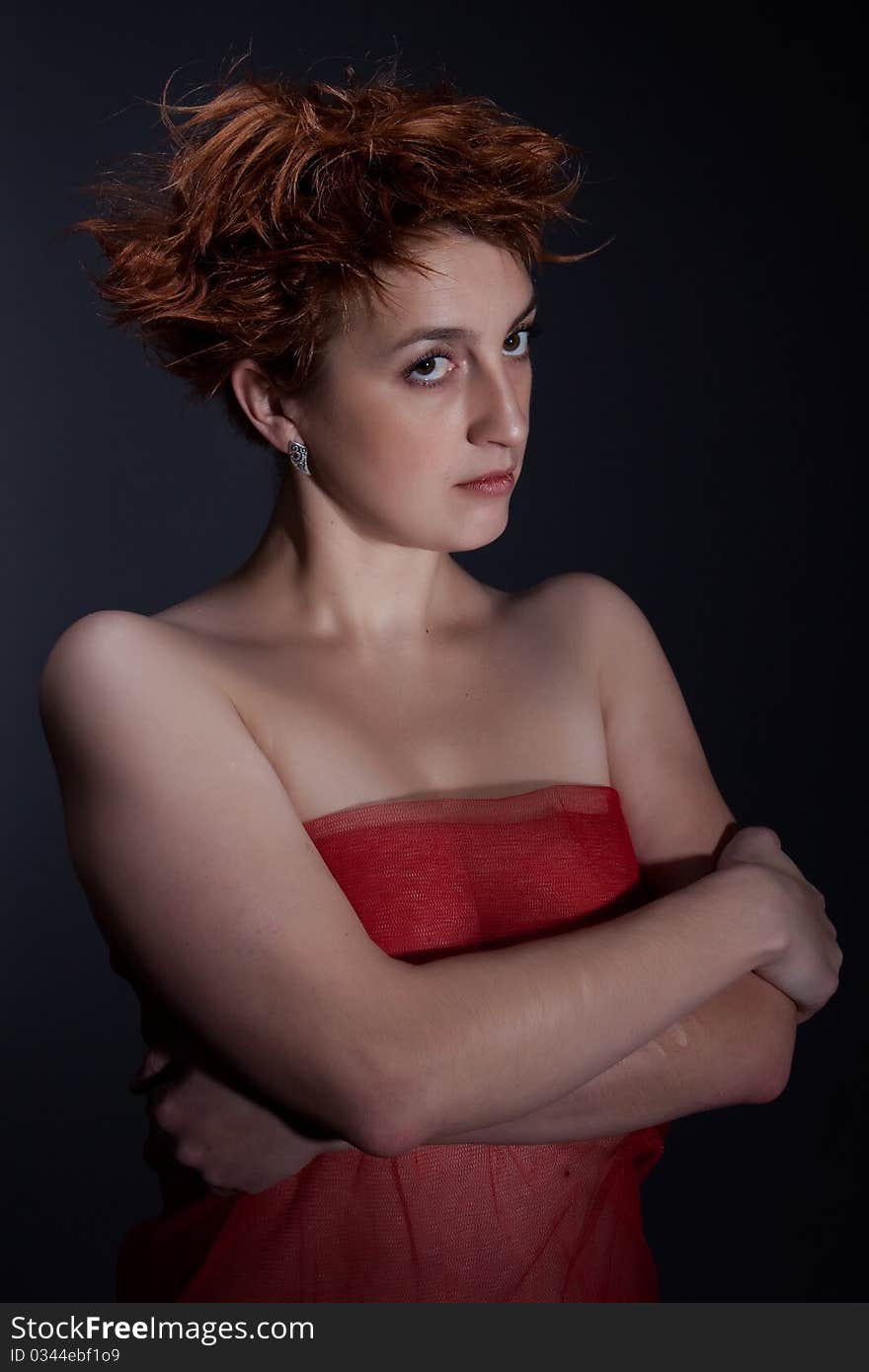 Portrait the red girl against a dark background dressed in a red