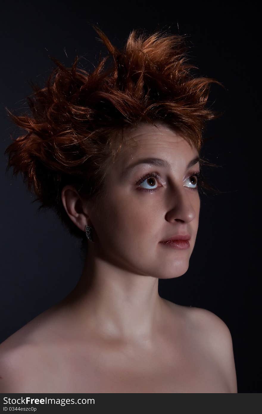 Portrait the red girl against a dark background dressed in a boa