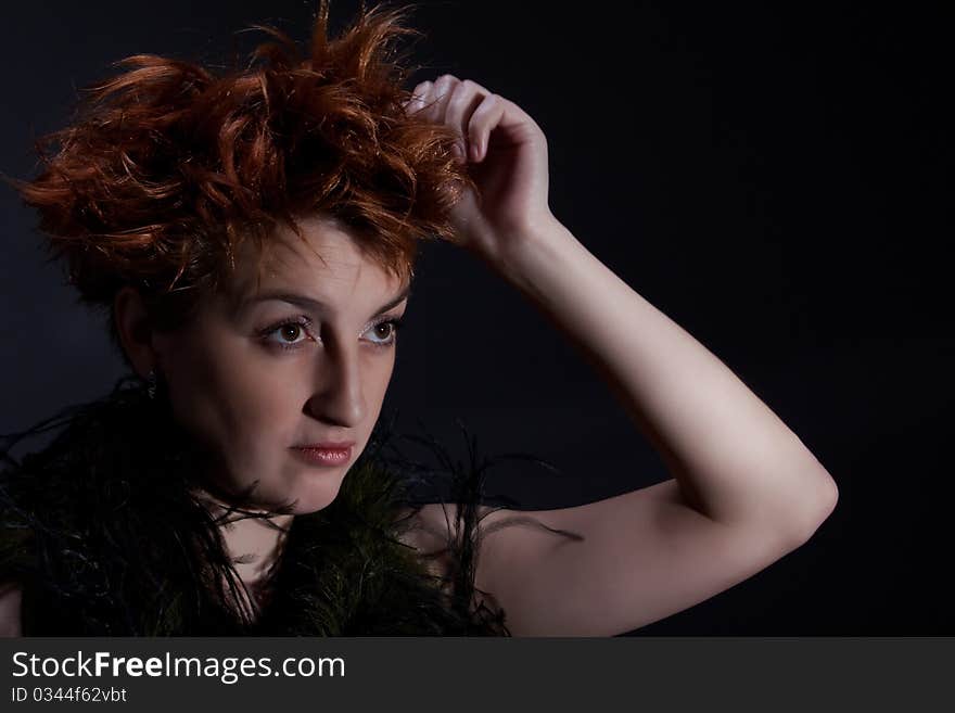 Portrait the red girl against a dark background dressed in a boa