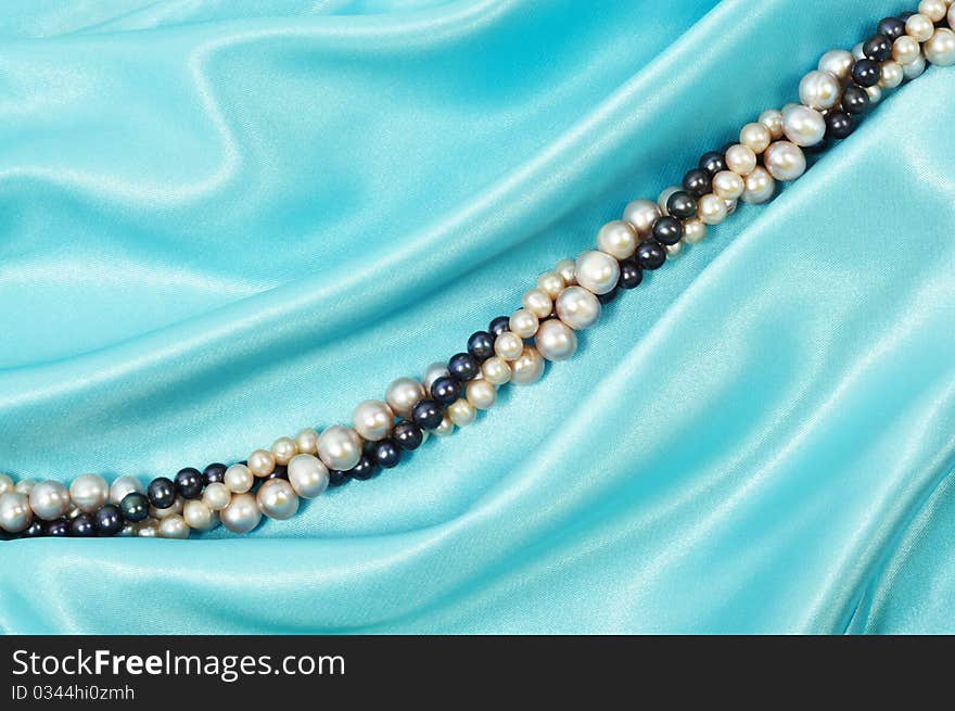 Blue silk background with pearl necklace on it. Blue silk background with pearl necklace on it