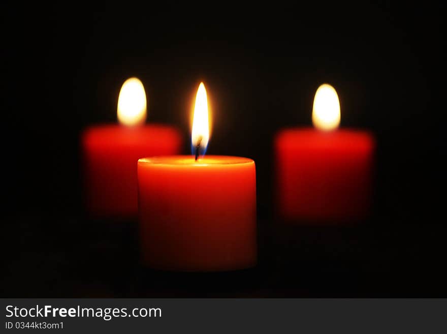 Three Red candles lit against black