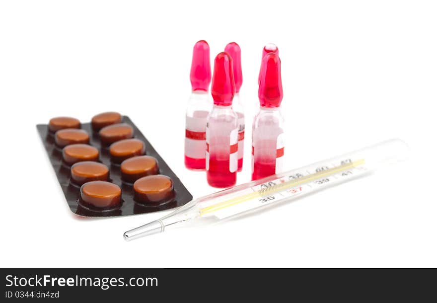 Ampoule, a thermometer and pills on a white background