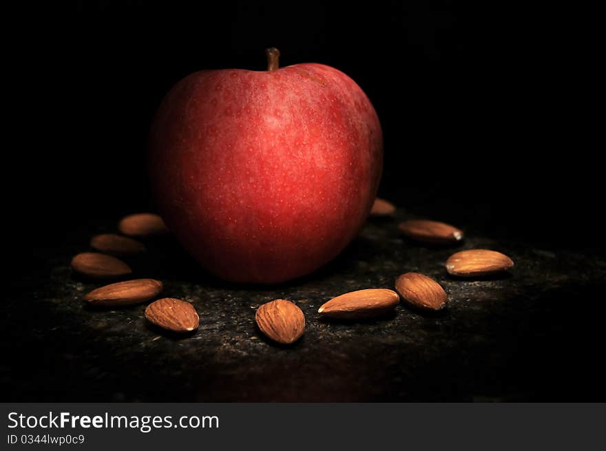 Healthy apple in the middle of a arranged circle of nuts. These fruits are being illuminated by long exposure and a light painting. Healthy apple in the middle of a arranged circle of nuts. These fruits are being illuminated by long exposure and a light painting