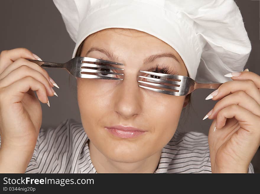 Portrait of a pretty young smiling  uniformed female Chef looking through forks