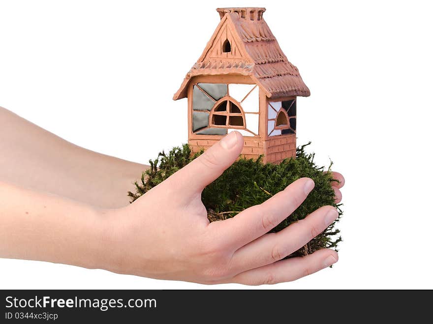 Clay house on moss in hand over white. Clay house on moss in hand over white