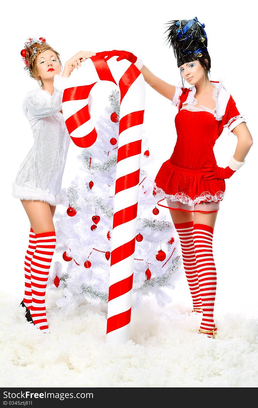 Two beautiful young women in Christmas clothes posing with a big candy. Two beautiful young women in Christmas clothes posing with a big candy.