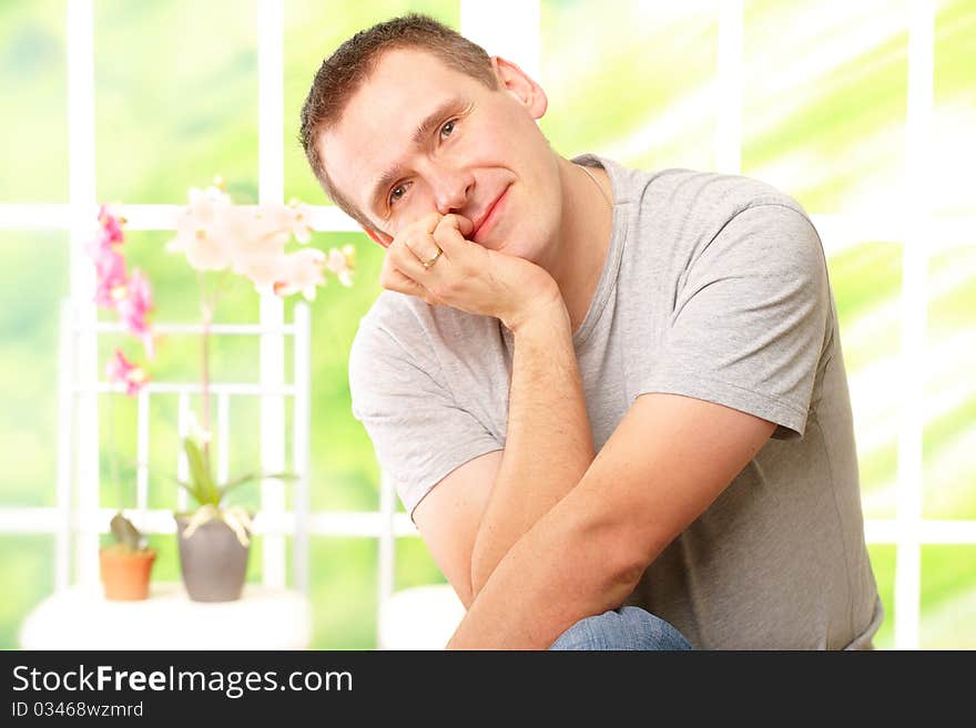 Handsome man resting at home lost in though and gently smiling.